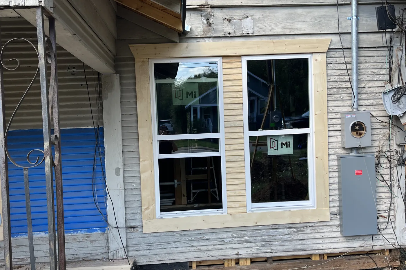 A house on 13th Street with siding stripped back and new windows being fitted